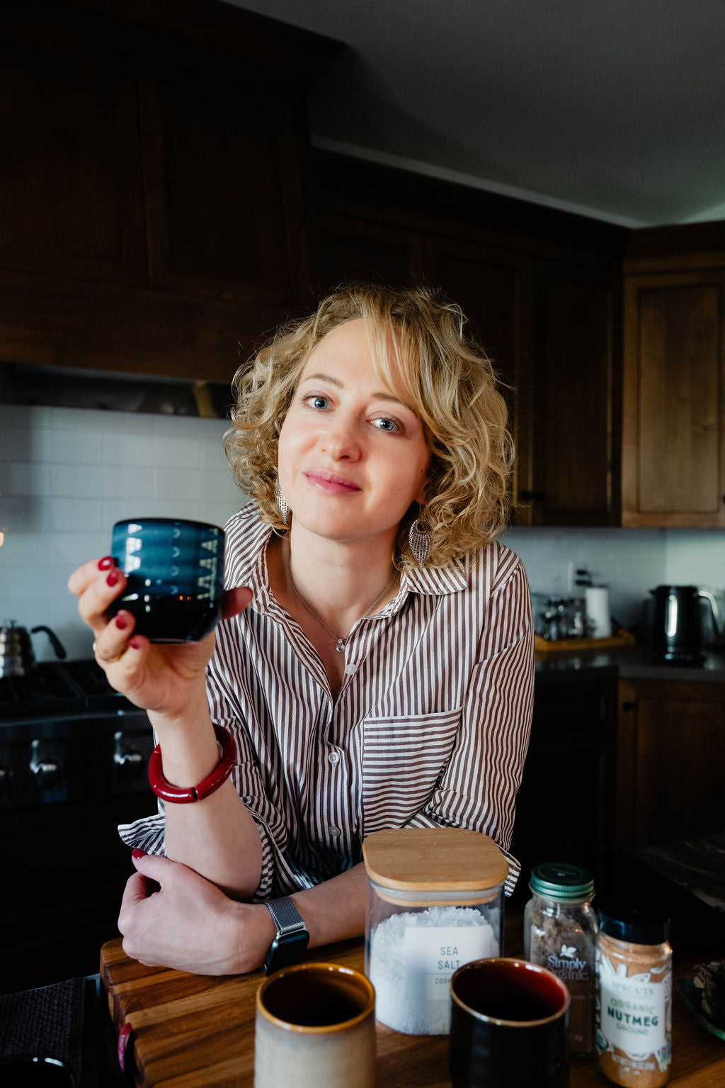 Woman holding a blue mug in a kitchen setting